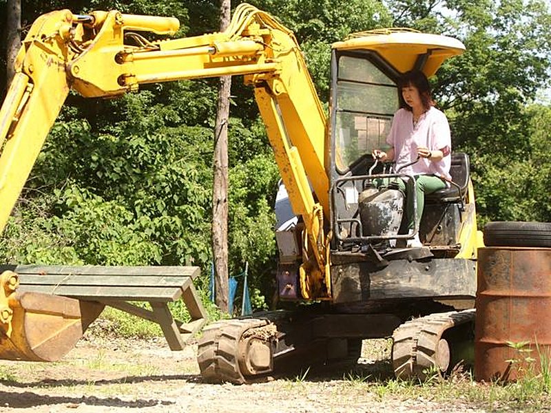 ユンボの運転席でアームを操作する参加者