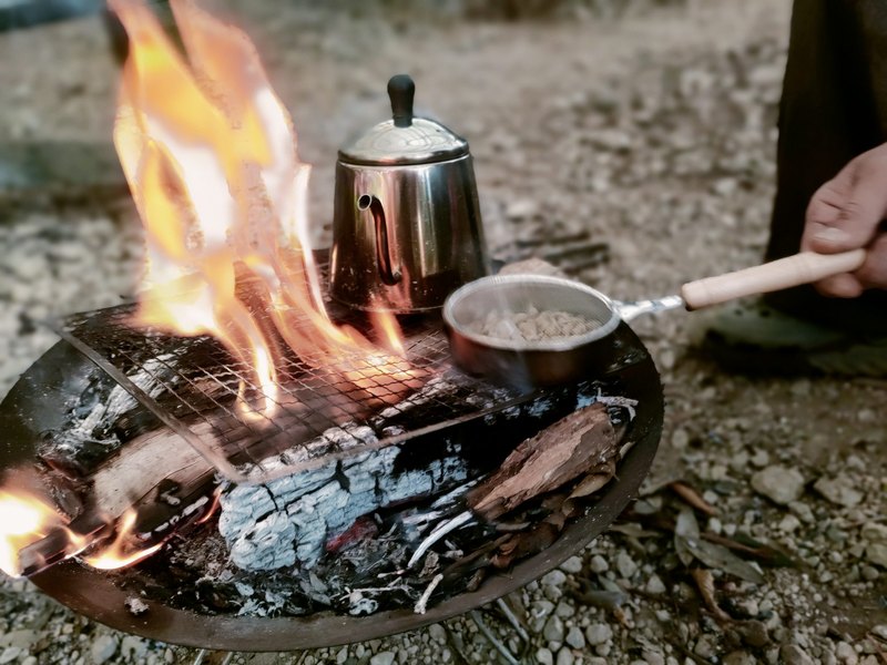 焚き火にかけたケトルと、生豆をローストする網