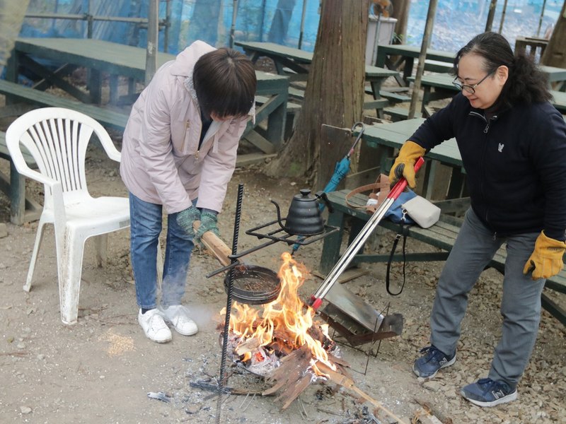 屋根付きエリアのベンチのそばで焚き火をおこす様子